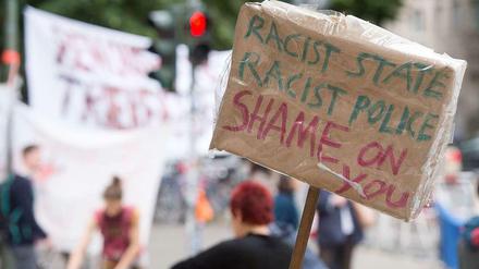 "Rassistischer Staat, rassistische Polizei, Schande über Euch" steht auf einem Schild bei der Gerhart-Hauptmann-Schule.