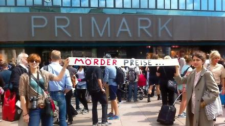 Zwei Frauen halten ein Banner mit der Aufschrift "Mörderpreise" vor der neuen Filiale in die Höhe.
