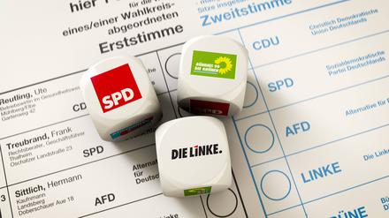 Stimmzettel zur Bundestagswahl, auf dem drei Würfel liegen, der Wurf ergab eine Koalition zwischen SPD, Die Linke und Die Grünen, Rot-Rot-Grün.