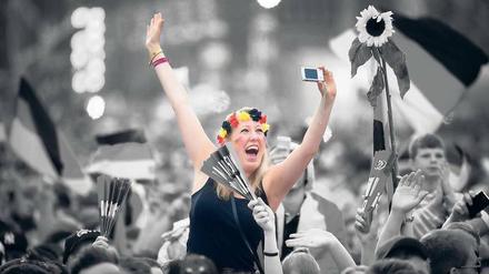 Mitten in der Menge - und doch nur sich selbst im Blick: Eine junge Frau macht auf der Fanmeile ein Jubel-Selfie von sich.