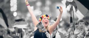 Mitten in der Menge - und doch nur sich selbst im Blick: Eine junge Frau macht auf der Fanmeile ein Jubel-Selfie von sich.