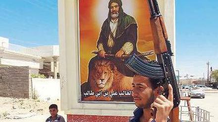 Kampfbereit: Ein Schiit patrouilliert vor einen Denkmal in Kirkuk.