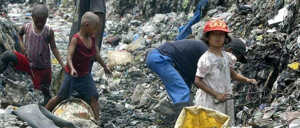 Philippinische Kinder durchsuchen eine Müllhalde nach brauchbaren Materialien.