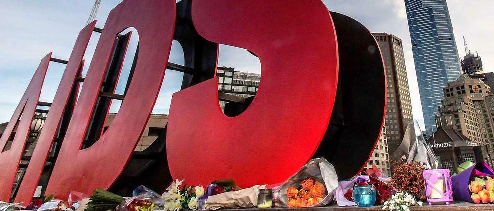 Überdimensionale plastische Buchstaben formen das Wort Aids, darunter sind Blumen abgelegt.
