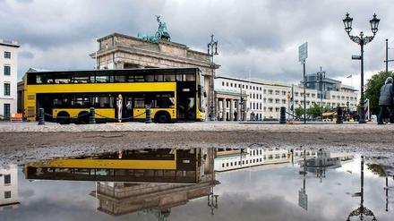 Doppeldecker fährt am Brandenburger Tor in Berlin entlang.