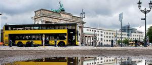 Doppeldecker fährt am Brandenburger Tor in Berlin entlang.