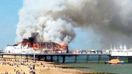 Fassungslos sehen Badegäste am Strand von Eastbourne, wie das Pier abbrennt.