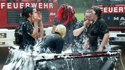 Mitglieder der Feuerwehr in Gudensberg (Hessen) baden am 29.05.2014 in einem Faltbecken mit Wasser und Badeschaum für ein Videoclip, mit dem die Feuerwehr sich bei dem Spektakel "Cold Water Challenge" beteiligte.