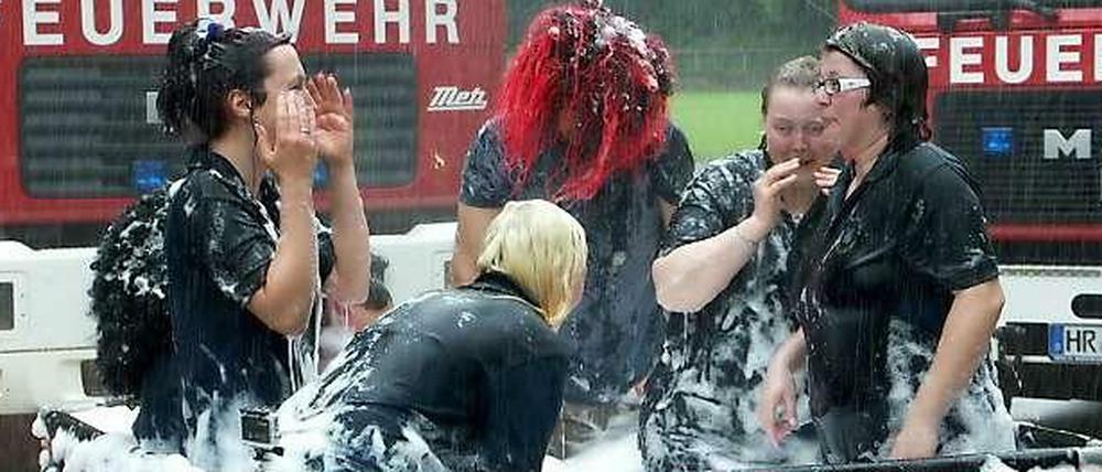Mitglieder der Feuerwehr in Gudensberg (Hessen) baden am 29.05.2014 in einem Faltbecken mit Wasser und Badeschaum für ein Videoclip, mit dem die Feuerwehr sich bei dem Spektakel "Cold Water Challenge" beteiligte.