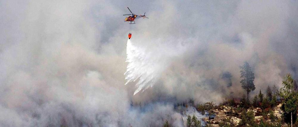 Ein einsamer Hubschrauber versucht die Flammen in den schwedischen Wäldern zu löschen.