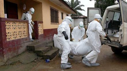 Ein Ebola-Opfer wird aus einem Haus in Liberia getragen. Ein Mitarbeiter des Gesundheitsdienstes desinfiziert das Haus, um eine Ansteckung seiner Bewohner weniger wahrscheinlich zu machen. 