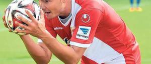 Fabian Schönheim hält einen Fußball ganz nah vor sein Gesicht.