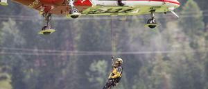 Von einer Hubschrauberbesatzung lässt sich ein Retter zu einem am Abgrund hängengebliebenen Waggon bei Tiefencastel abseilen.