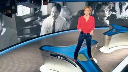 Große Geste. Caren Miosga steigt auf den Moderatorentisch und erinnert an eine besondere Filmszene mit Robin Williams.