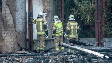 Brandruine: Feuerwehrleute begutachten nach den Löscharbeiten die vom Feuer zerstörten Kulissen-Häuser im Spreepark. 