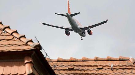 Ein Passagierflugzeug fliegt direkt über den Hausdächern. Rund um den BER hat noch kein Haus Schutzfenster nach Vorschrift.