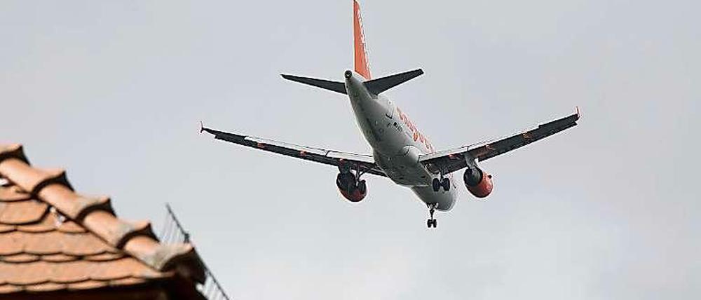 Ein Passagierflugzeug fliegt direkt über den Hausdächern. Rund um den BER hat noch kein Haus Schutzfenster nach Vorschrift.