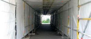 Der Parkweg unter der Brücke ist nur durch diesen Bau-Tunnel passierbar