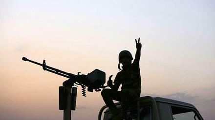 Ein kurdischer Kämpfer gegen die IS-Milizen zeigt im Irak auf einem Autodach.