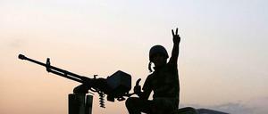 Ein kurdischer Kämpfer gegen die IS-Milizen zeigt im Irak auf einem Autodach. 
