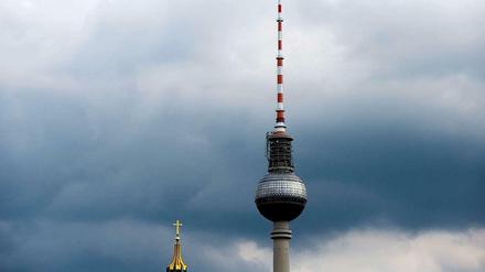 Eine der vielen Ideen, wie das Klima künstlich beeinflusst werden könnte, ist die technische Aufhellung von Wolken, damit mehr Sonnenlicht in den Weltraum abgestrahlt wird und die Erdoberfläche gar nicht erst erreichen kann. Das Foto zeigt den Berliner Fernsehturm und die Spitze der Marienkirche vor dunklen Regenwolken. 