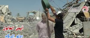 Der palästinensische Journalist Ayman al-Aloul in Gaza kippt sich einen Eimer voll Schutt über den Kopf. 