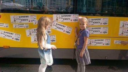 Marlene und Emilia kleben die "Vorfahrt für Kinder"-Sticker auf einen BVG-Bus. Am Sonnabend werden die Mädchen eingeschult.
