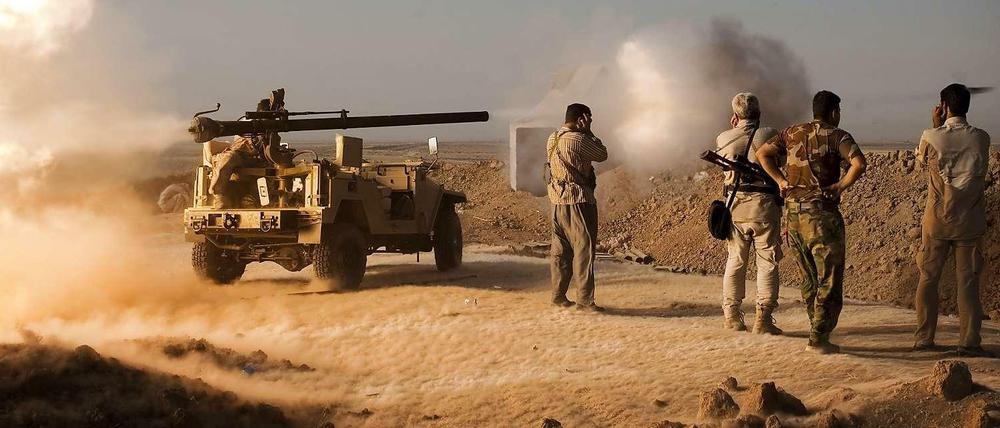 Kurdische Peschmerga-Kämpfer feuern in Richtung von IS-Stellungen. 