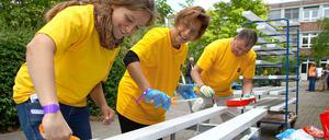 Bänker streichen Bänke: Mitarbeiter der Berliner Bank bei der Neugestaltung des Schulgartens an der Friedensburg am Aktionstag 2012.