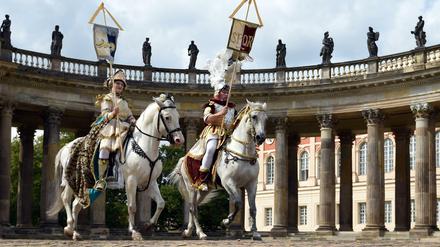 Olympisches Dressurreiten? Na, fast. Wolfgang und Diana Krischke posieren in historischen Kostümen auf ihren Pferden vor den Kolonnaden in Sanssouci. Zur Wiedereröffnung der sanierten Kolonnaden soll vor der historischen Kulisse am 11. September eine barocke Pferdeoper mit 24 Tieren stattfinden – und 2024 vielleicht Olympia.