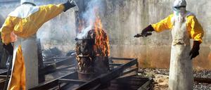 Helfer verbrennen benutzte Schutzkleidung im Ärzte-ohne-Grenzen-Zentrum in Conakry. Die Ebola-Epidemie könnte sich noch erheblich ausweiten.