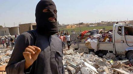 Ein Kämpfer der Terrormiliz IS steht vor den Trümmern eines Hauses in Raka, das angeblich zerstört wurde durch den Absturz eines syrischen Kampfflugzeuges, das von IS-Kämpfern abgeschossen worden sei.