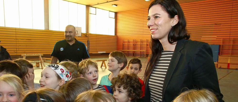 Senatorin Scheeres steht mit Schülern in einer Turnhalle.