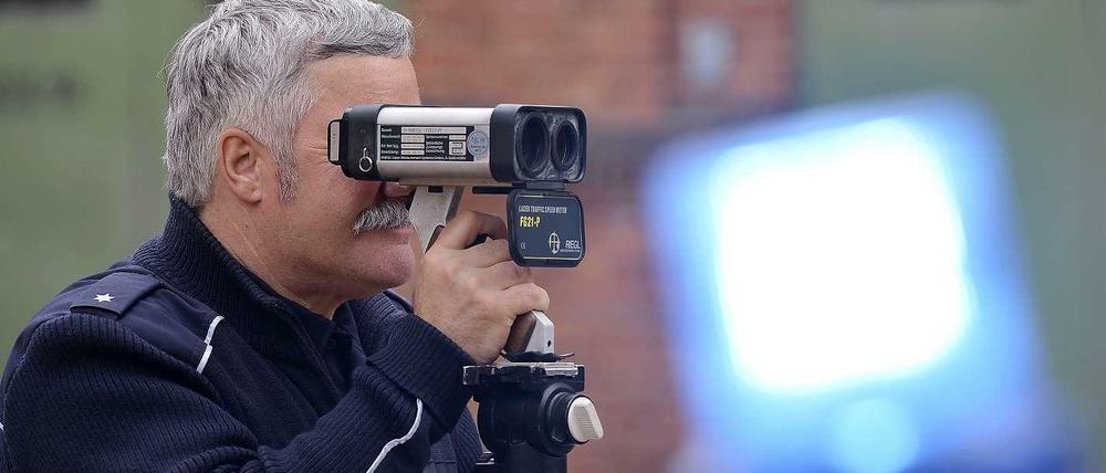 Ein Polizeibeamter blickt durch den Sucher eines Tempo-Messgeräts.
