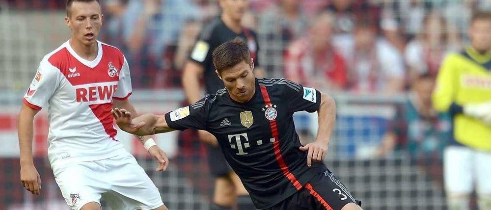 Weltmeisterliche Pose: Bayern-Spieler Xabi Alonso trotzt der Schwerkraft,d er Kölner Adam Matuschyk (l.) staunt.