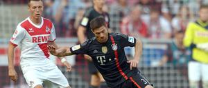 Weltmeisterliche Pose: Bayern-Spieler Xabi Alonso trotzt der Schwerkraft,d er Kölner Adam Matuschyk (l.) staunt.