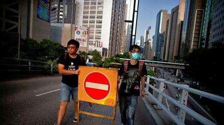 Zwei Demonstranten in der Nähe des Regierungsviertels in Hongkong tragen ein Straßenschild.