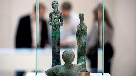 Drei Skulpturen stehen in einer Glasvitrine.
