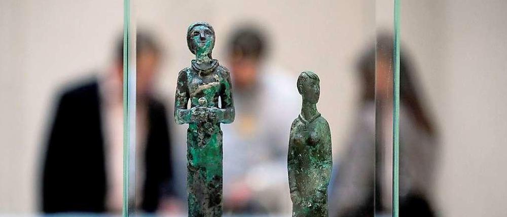 Drei Skulpturen stehen in einer Glasvitrine.