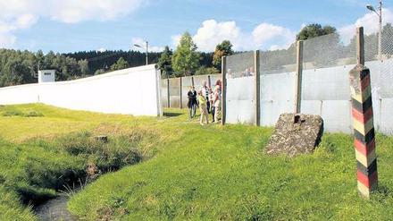 Mödlareuth. Der Ort wird bisweilen auch gern Klein-Berlin genannt. Damals, als Deutschland geteilt war. Was natürlich falsch war. Schließlich lag das zerschnittene Berlin mitten in der DDR. Doch auch durch Mödlareuth verlief eine Grenze. Zwischen Bayern und Thüringen. Das hat sich nicht geändert. Auch ein Mauerstück und andere Grenzanlagen sind am Ort geblieben. 