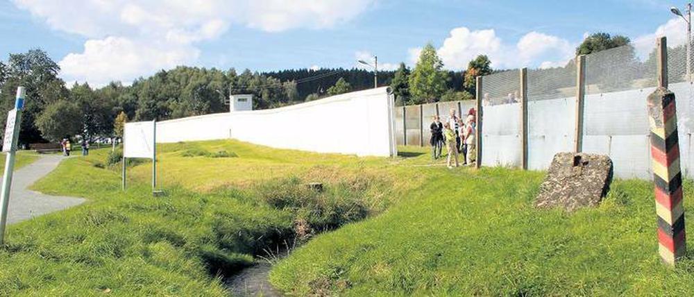 Mödlareuth. Der Ort wird bisweilen auch gern Klein-Berlin genannt. Damals, als Deutschland geteilt war. Was natürlich falsch war. Schließlich lag das zerschnittene Berlin mitten in der DDR. Doch auch durch Mödlareuth verlief eine Grenze. Zwischen Bayern und Thüringen. Das hat sich nicht geändert. Auch ein Mauerstück und andere Grenzanlagen sind am Ort geblieben. 