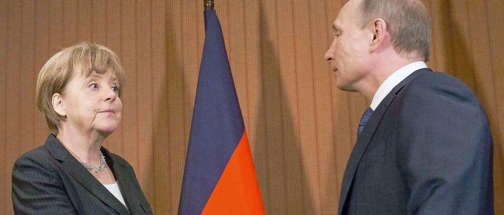 Kanzlerin Angela Merkel und der russische Präsident Wladimir Putin reichen einander die Hand.