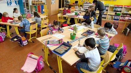 Grundschüler sitzen in ihrem Klassenraum und schreiben auf Arbeitsbögen.