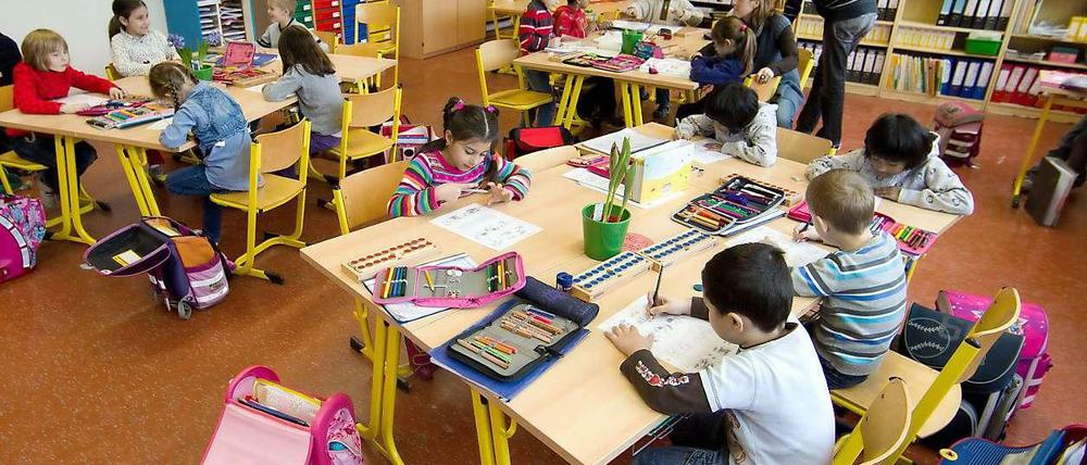 Grundschüler sitzen in ihrem Klassenraum und schreiben auf Arbeitsbögen.