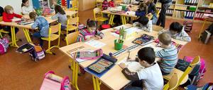 Grundschüler sitzen in ihrem Klassenraum und schreiben auf Arbeitsbögen.