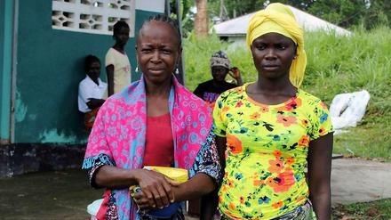 Zwei Frauen, die Ebola überlebt haben, lassen sich vor einer Klinik in Liberia fotografieren. Überlebende haben große Probleme in ihren Dörfern oder Nachbarschaften wieder aufgenommen zu werden. Denn die Angst vor einer Ansteckung ist so groß, dass sie fast überall gemieden werden.