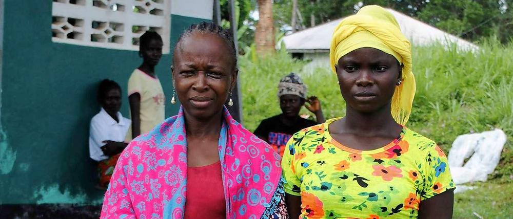 Zwei Frauen, die Ebola überlebt haben, lassen sich vor einer Klinik in Liberia fotografieren. Überlebende haben große Probleme in ihren Dörfern oder Nachbarschaften wieder aufgenommen zu werden. Denn die Angst vor einer Ansteckung ist so groß, dass sie fast überall gemieden werden.