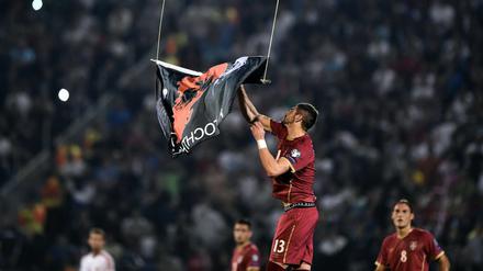 Serbiens Stefan Mitrovic reißt die Großalbanien-Fahne von der Drohne, die über dem Stadion ihre Runden fliegt.