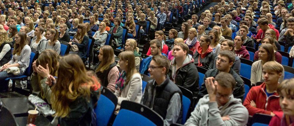 Studienanfänger sitzen in einem vollen Hörsaal.