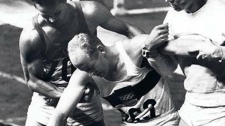 Gestützt von den Konkurrenten. Willi Holdorf wird vom sowjetischen Silbermedaillengewinner Rein Aun (links) und dem Wolfsburger Horst Beyer im Ziel aufgerichtet.